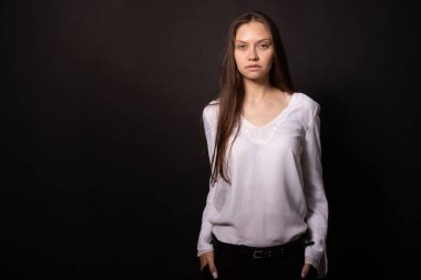 Uzun düz saçlı güzel kız dik duruyor, doğrudan kameraya bakıyor.