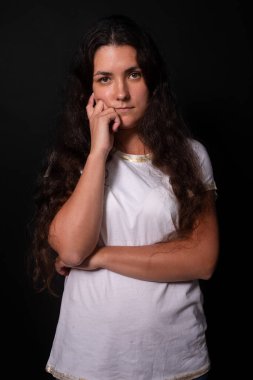 Genç kız dalgın dalgın bakıyor. Elle yanak. Siyah arka plan. İnsan duyguları