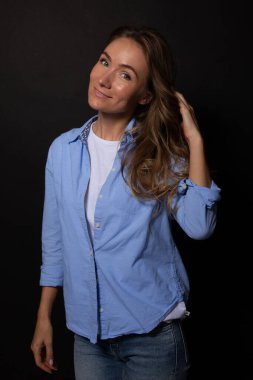 Güzel bir kadın kameraya gülümseyerek bakar. El saçı tutar. Siyah arkaplan