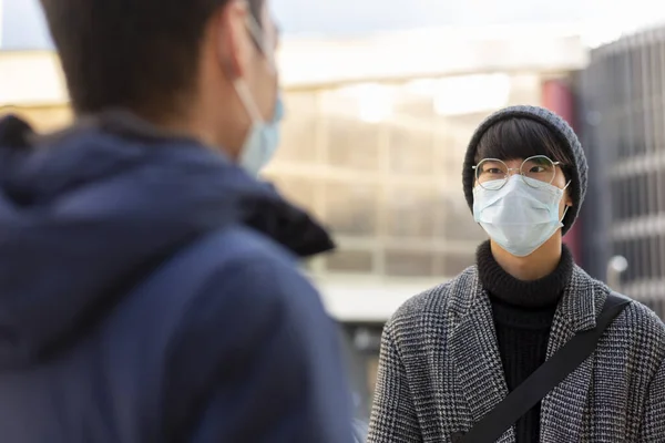 Dos jóvenes asiáticos en máscaras protectoras médicas contra covid-2019 hablando —  Fotos de Stock