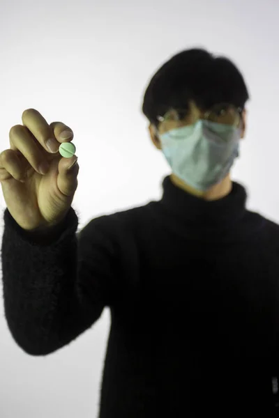 Chinese man in facial mask, focus on pill in hand. Prevent spread of coronavirus