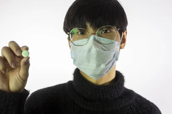 Asian young man in glasses, protective mask against covid-19 with pill in hand — Stock Photo, Image