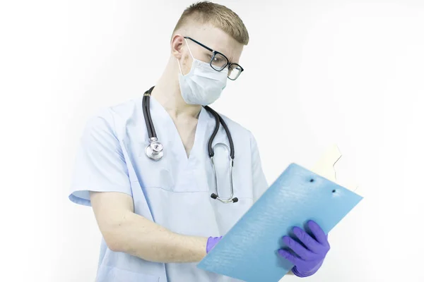 Young lab technician in uniform and stethoscope writing on blue clipboard — Stock Photo, Image