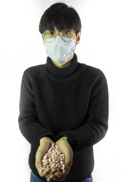 Asian man in facial mask, handful of pills. Pandemic disease. Virus protection — Stock Photo, Image