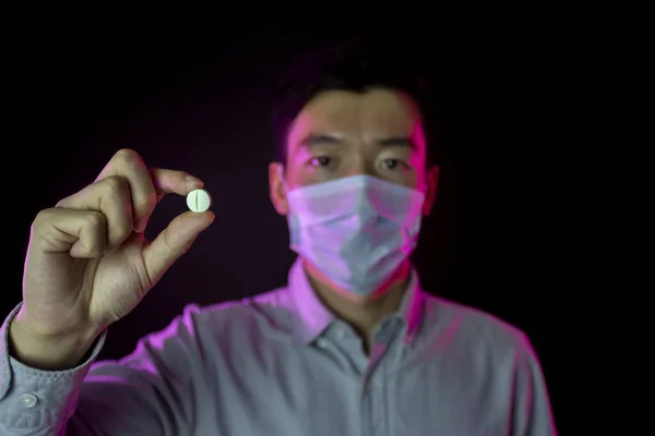 Asiatisk man med medicinsk skyddsmask. Fokus på piller mot covid-2019 i handen — Stockfoto