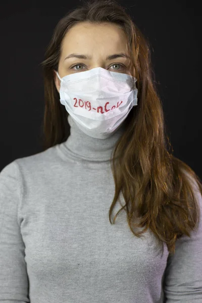 Retrato de mujer asustada de coronavirus en máscara médica con 2019-ncov escrito — Foto de Stock