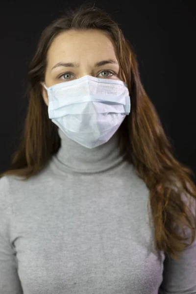 Portrait woman scared coronavirus in medical mask close-up black studio isolated