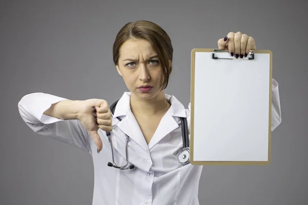 Unzufriedener Arzt mit leerem Klemmbrett zeigt Zeichen der Abneigung mit gesenktem Daumen — Stockfoto