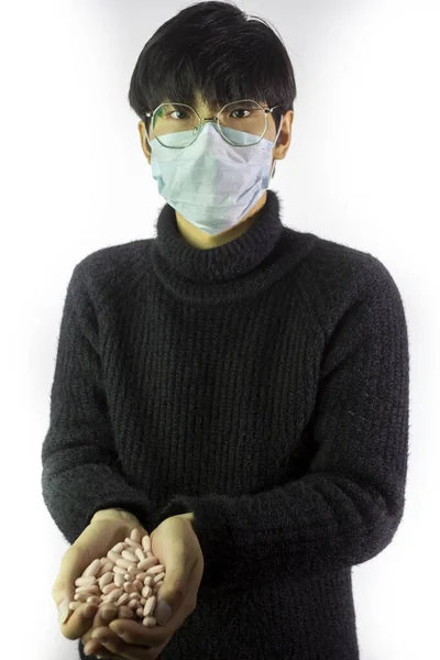 Hombre chino con máscara facial, un puñado de pastillas. Enfermedad pandémica. Protección contra virus —  Fotos de Stock