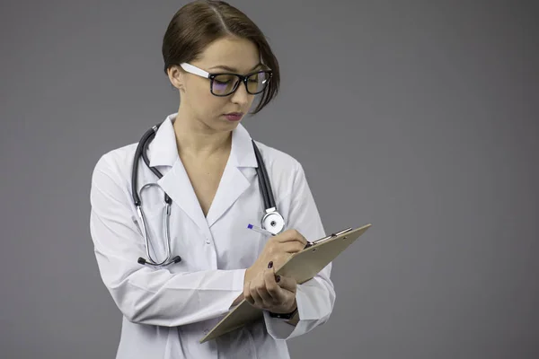 Seriuos sexy Arzt in weißem Mantel, Stethoskopschrift auf Klemmbrett, Kopierraum — Stockfoto