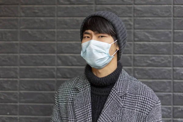 Chinese man in surgical mask against covid-2019 looks miserable and sad. Outside — Stock Photo, Image