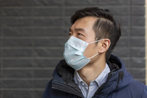Kinesisk kille i medicinsk mask mot covid-19 tittar åt sidan. Utanför — Stockfoto