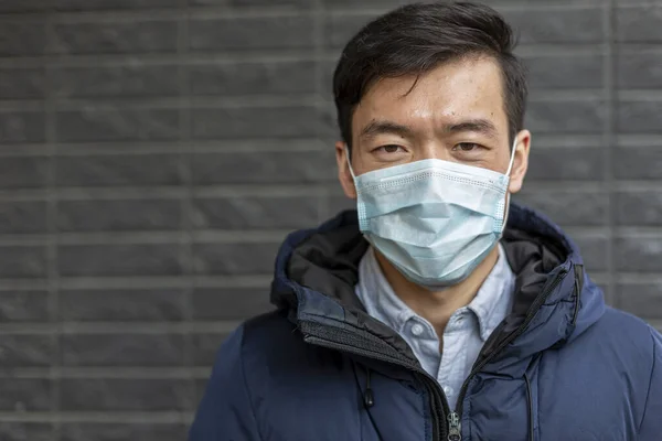 Retrato de hombre asiático en máscara quirúrgica. Covid-2019. Afuera. Fondo gris —  Fotos de Stock