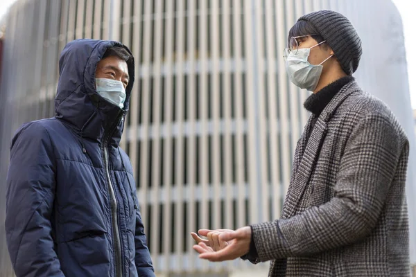 Två asiatiska män i ansiktsmasker. Utanför. Covid-2019. Skydd av virus — Stockfoto
