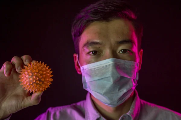 Kinesisk man i ansiktsmask mot 2019-nCov, spetsig boll som liknar coronavirus — Stockfoto