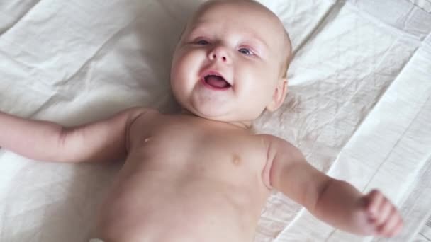 Счастливо улыбающийся новорожденный малыш на кровати пытается разговаривать — стоковое видео