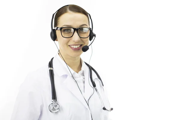 Schöne sexy Ärztin im weißen Mantel, Headset blickt lächelnd in die Kamera — Stockfoto