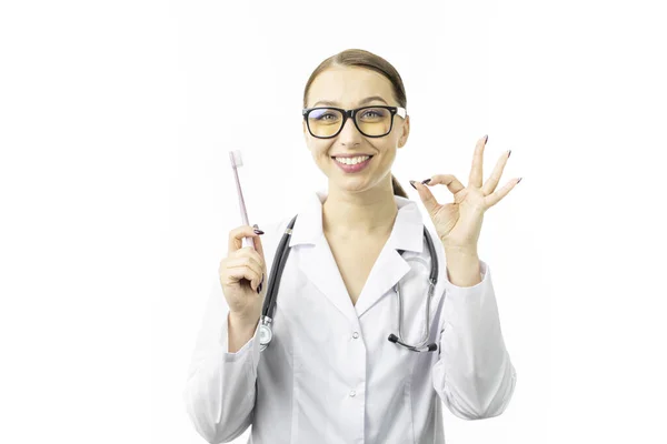 Porträt einer sexy Zahnärztin im Arztkittel zeigt Zahnbürste und Ok-Geste. — Stockfoto