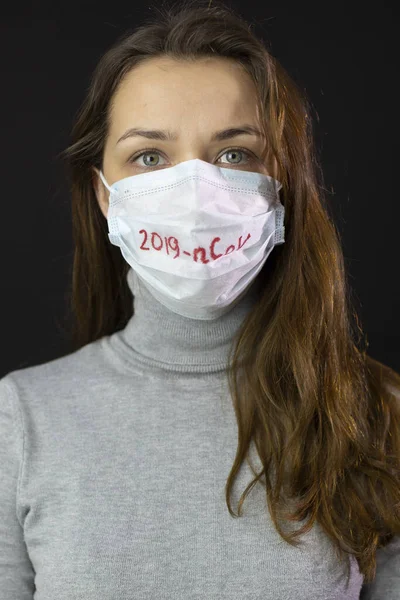 Retrato de mujer asustada de coronavirus en máscara médica con 2019-ncov escrito — Foto de Stock