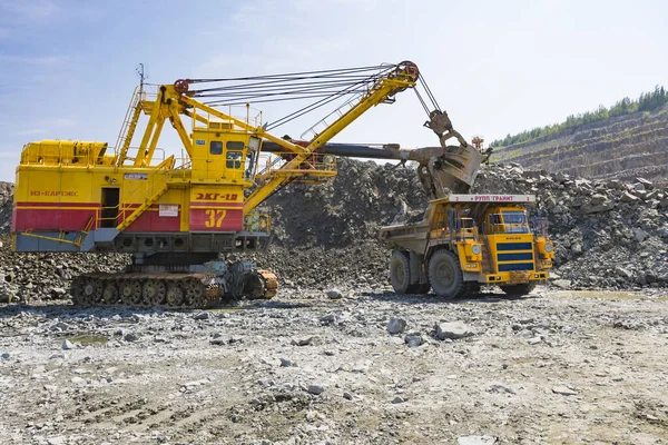Těžební rypadlo naloží obrovský náklaďák s žulovou skálou — Stock fotografie