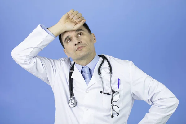 Portrét dospělého lékaře muž unavený držet ruce na hlavě pocit únavy. — Stock fotografie