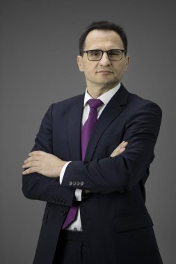 Resmi giyinmiş iş adamı kollarını kavuşturup kameraya bakıyor.