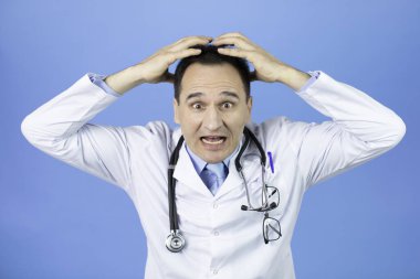 Şok olmuş doktor, mavi arka planda el üstünde korkuyla bağırıyor.