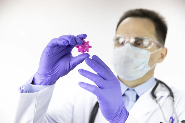 Labortechnikus orvosi egyenruhában, orvosi maszk a covid-19 vírussejt után. — Stock Fotó