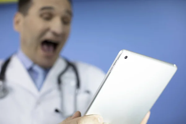 Porträt eines aufgeregten erwachsenen diagnostischen Arztes in Uniform, der auf ein Tablet blickt — Stockfoto