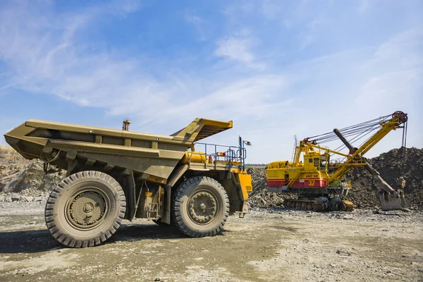 Těžební bagr nakládá těžký náklaďák s obrovskými žulovými stroji — Stock fotografie