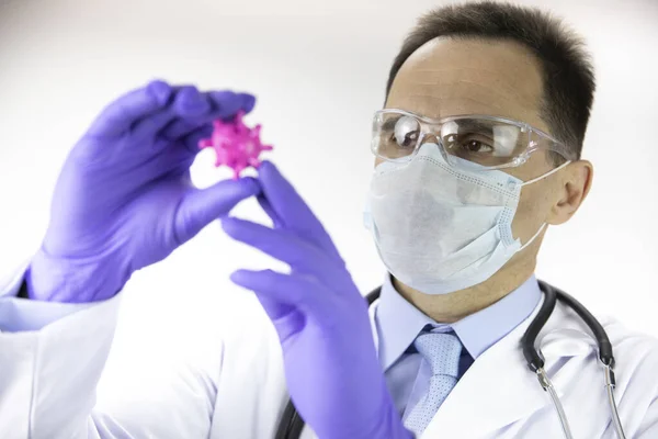 Orvos orvosi egyenruhában, védőmaszk és szemüveg nézi covid-19 sejt — Stock Fotó