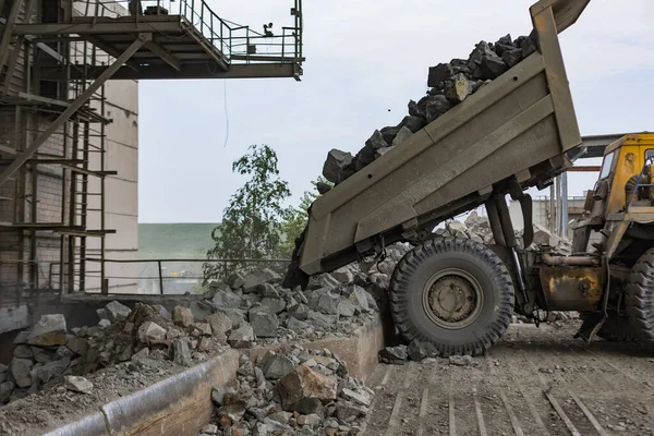 Těžební průmysl: těžká nákladní vozidla vyloží žulu do obrovského drtiče kamení — Stock fotografie