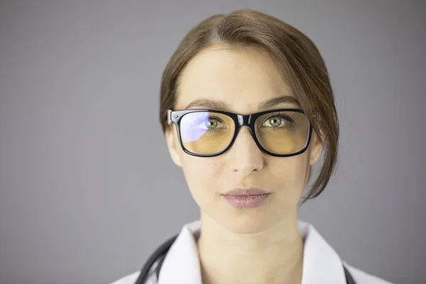 노란 렌즈가 달린 안경을 쓴 섹시 한 여의사가 카메라를 보고 있습니다 — 스톡 사진