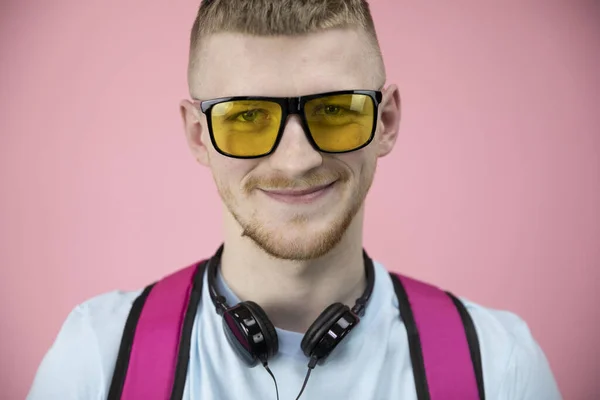 Portrait de garçon mignon dans des lunettes jaunes et écouteurs sur le cou sourit largement . — Photo