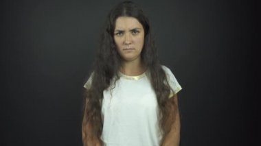 Tişörtlü ciddi bir kadın stüdyoda fotoğraf çekimi için poz veriyor.