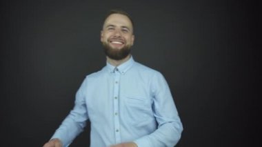 Mavi gömlekli yakışıklı adam neşeyle gülümsüyor.