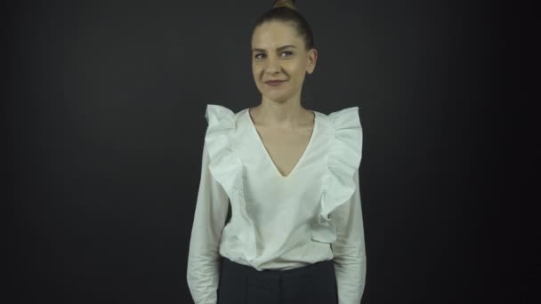 Dame in witte blouse kijkt rond met raadselachtige glimlach — Stockvideo