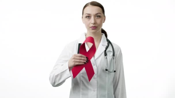 Улыбающийся красивый врач показывает красную ленточку на белом фоне — стоковое видео