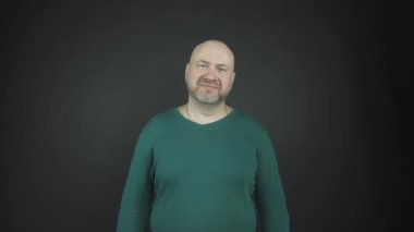 Gri sakallı kel adam düzgün görünüyor ve gülümsüyor.