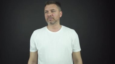 Sakallı yakışıklı adam ışık altında fotoğraf çekimi için poz veriyor.