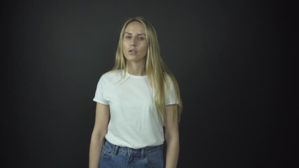 Serieuze dame in wit t-shirt en blauwe spijkerbroek staat — Stockvideo