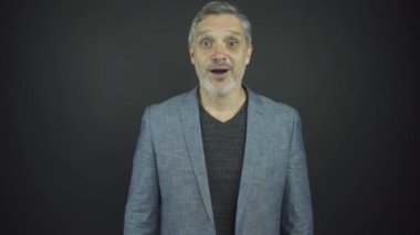 Gri sakallı, saçları olan yaşlı adam sürpriz ve neşe saçar.