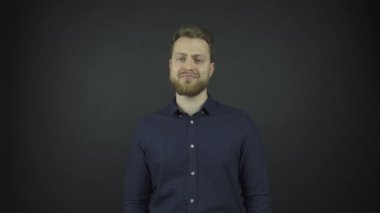 Sakallı mutlu adam parlak ışık altında konuşuyor ve gülüyor.