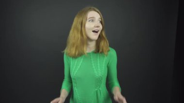 Heyecanlı kızıl kız gülümser ve duygularını ellerinin arkasına saklar.