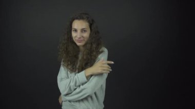 Gri kapüşonlu çekici esmer fotoğraf çekimi için poz veriyor.