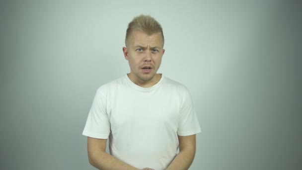 Šokovaný chlap v bílém tričku vypadá rovně a křičí — Stock video