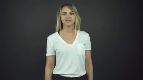 Atractiva rubia en camiseta blanca levanta las manos felizmente — Vídeo de stock