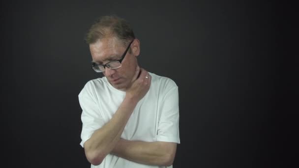 Eftertänksam man i t-shirt och glasögon står repande hals — Stockvideo