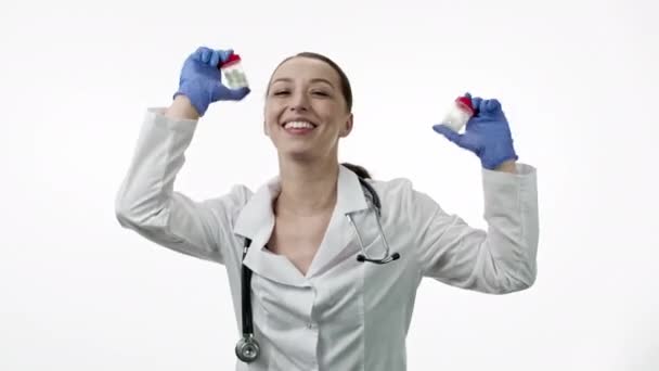 Забавный красивый улыбающийся доктор танцует с пачками таблеток в руках, веселится — стоковое видео