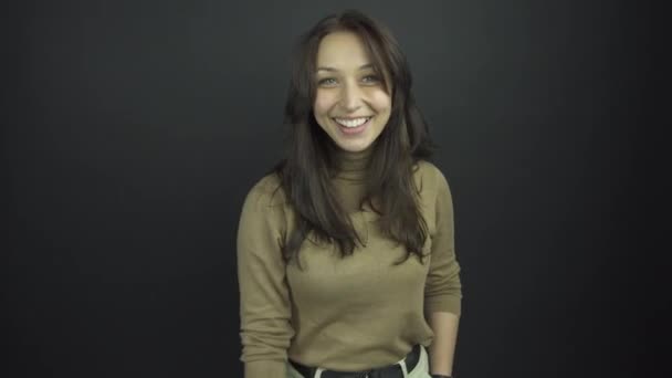 Vzrušená brunetka v hnědém roláku se usmívá a potřásá rukou — Stock video